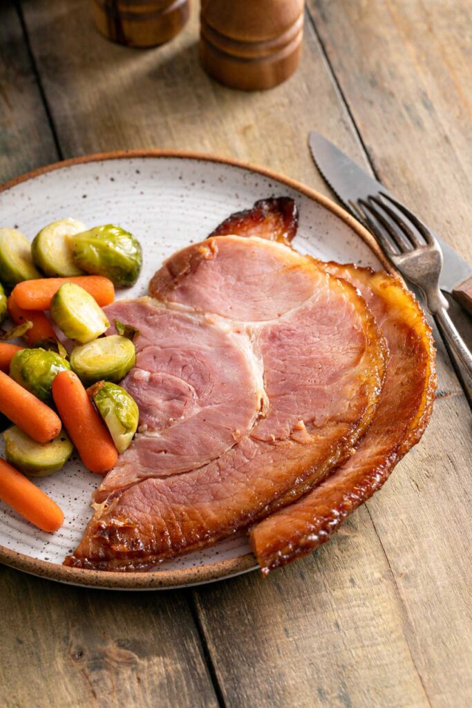 Slices of honey baked ham served with roasted veggies.