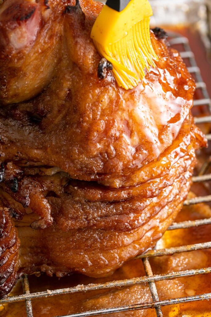 Brushing spiced brown sugar glaze on a spiral ham.