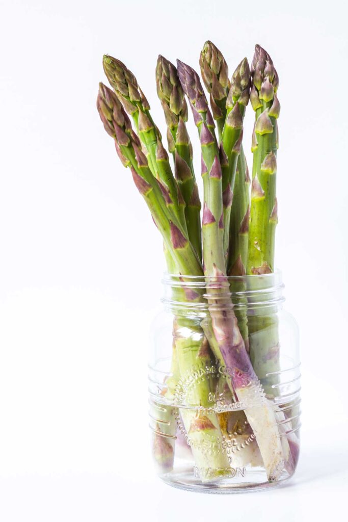 Asparagus on a small glass jar filled with water.