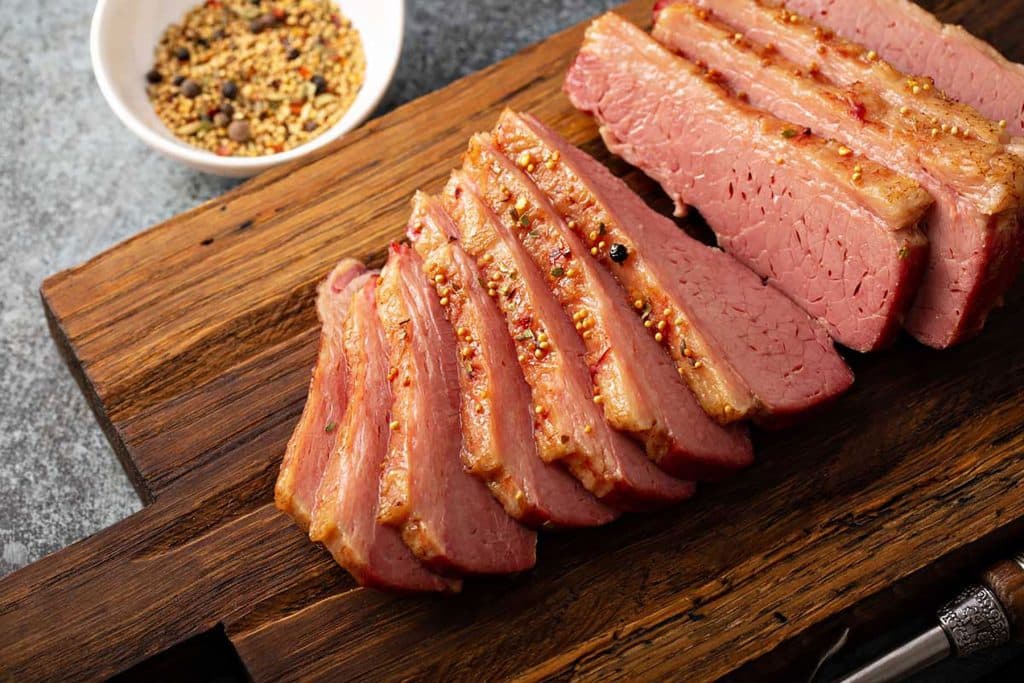 Sliced corned beef on a wooden cutting board.