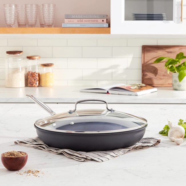 A 12 inch skillet with its lid over a kitchen towel in a kitchen countertop