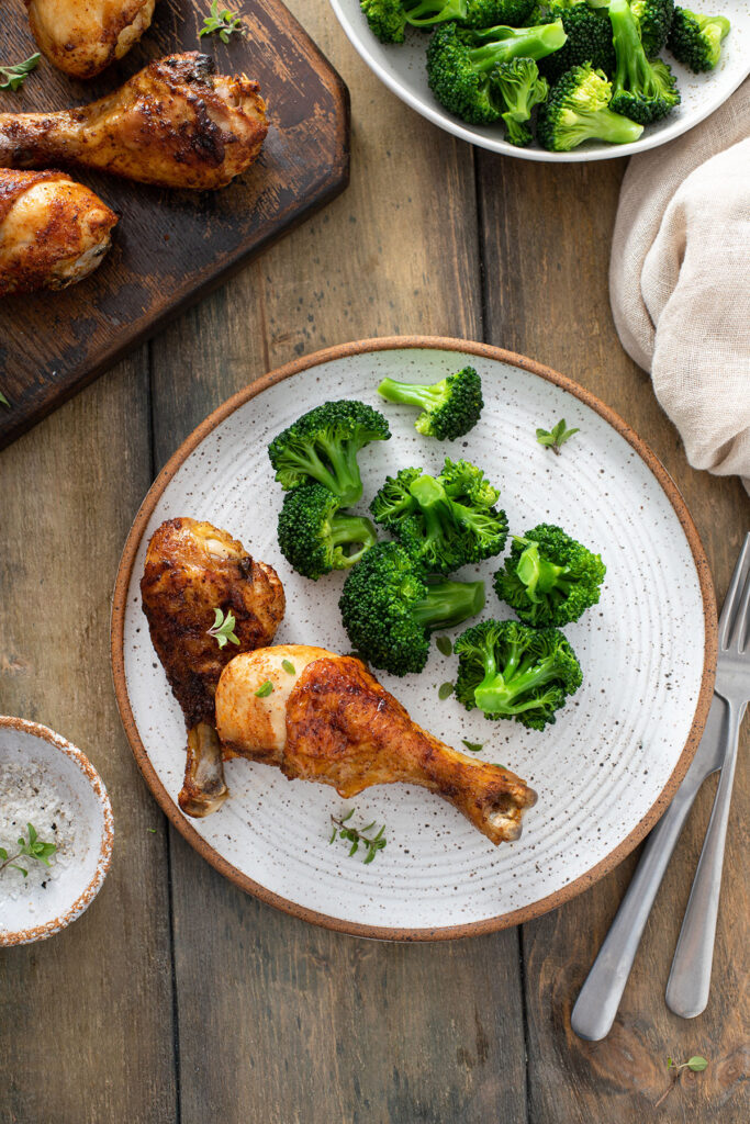 Crispy roasted chicken drumsticks served with broccoli on a plate
