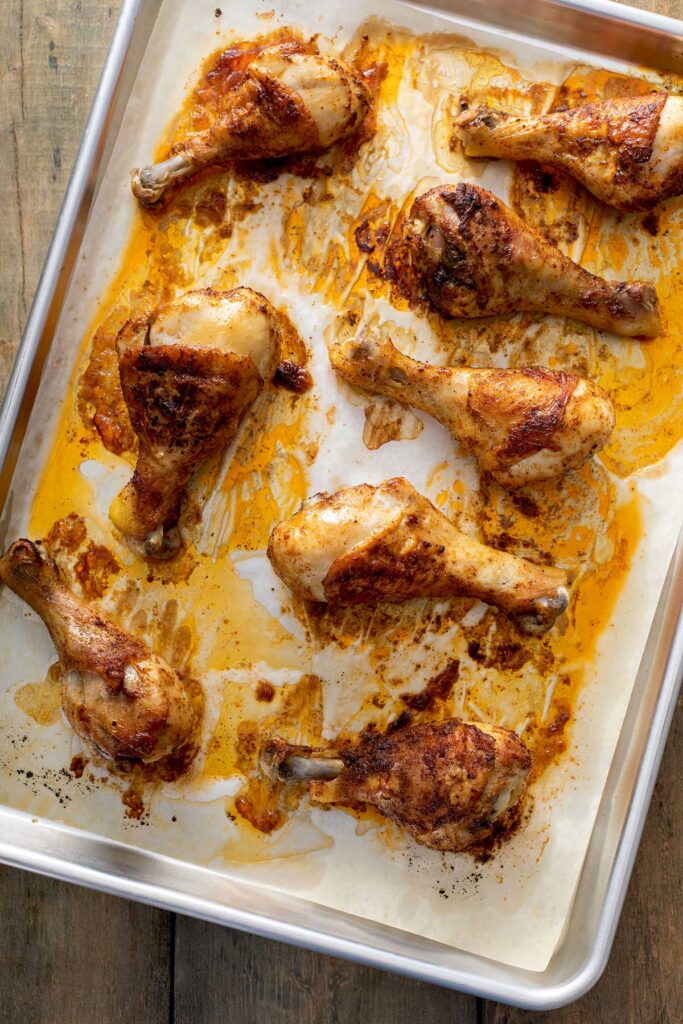 Juicy cooked chicken drumsticks on a sheet pan with parchment paper