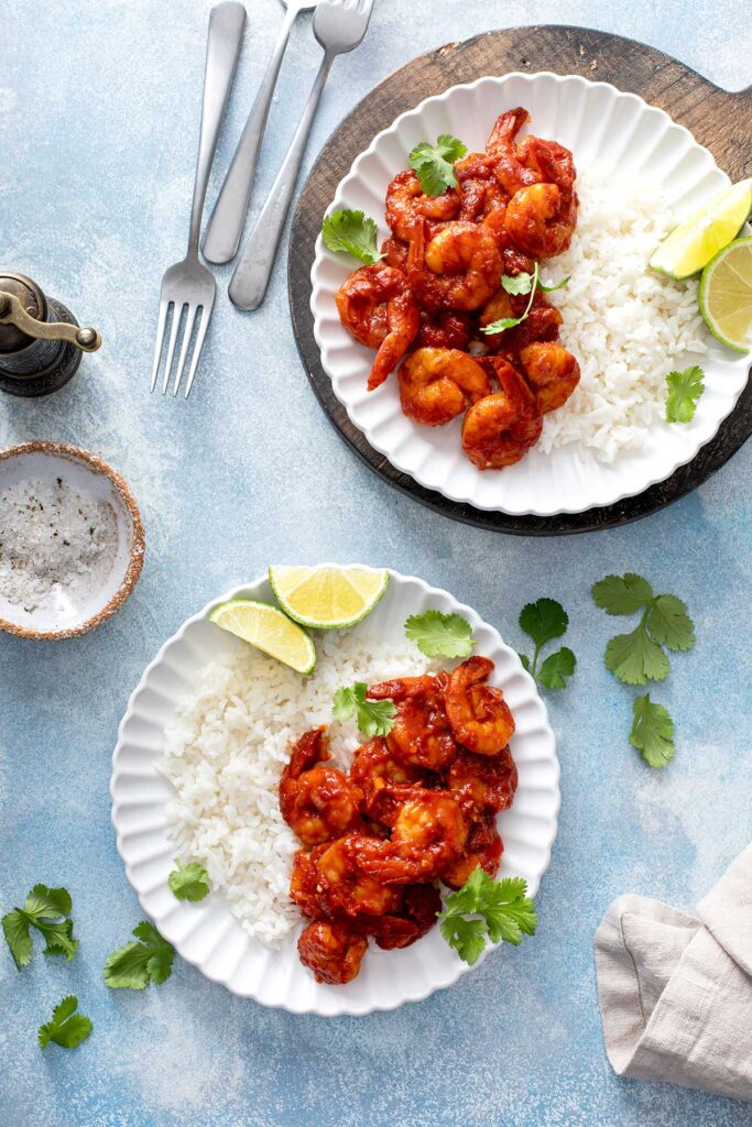 Plates with white rice and Mexican spicy shrimp in tomato chile sauce.