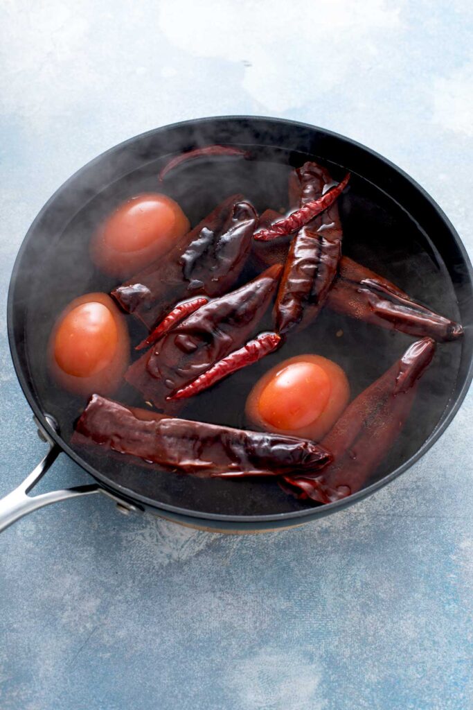 Dried chiles and whole tomatoes in a pot of boiling water