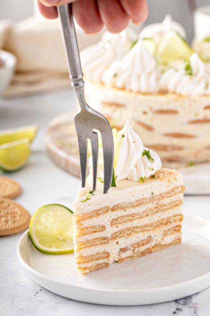 A slice of Carlota de Limón showing layers of cookies (capas de galletas Maria) sandwiched between a creamy lime mixture.