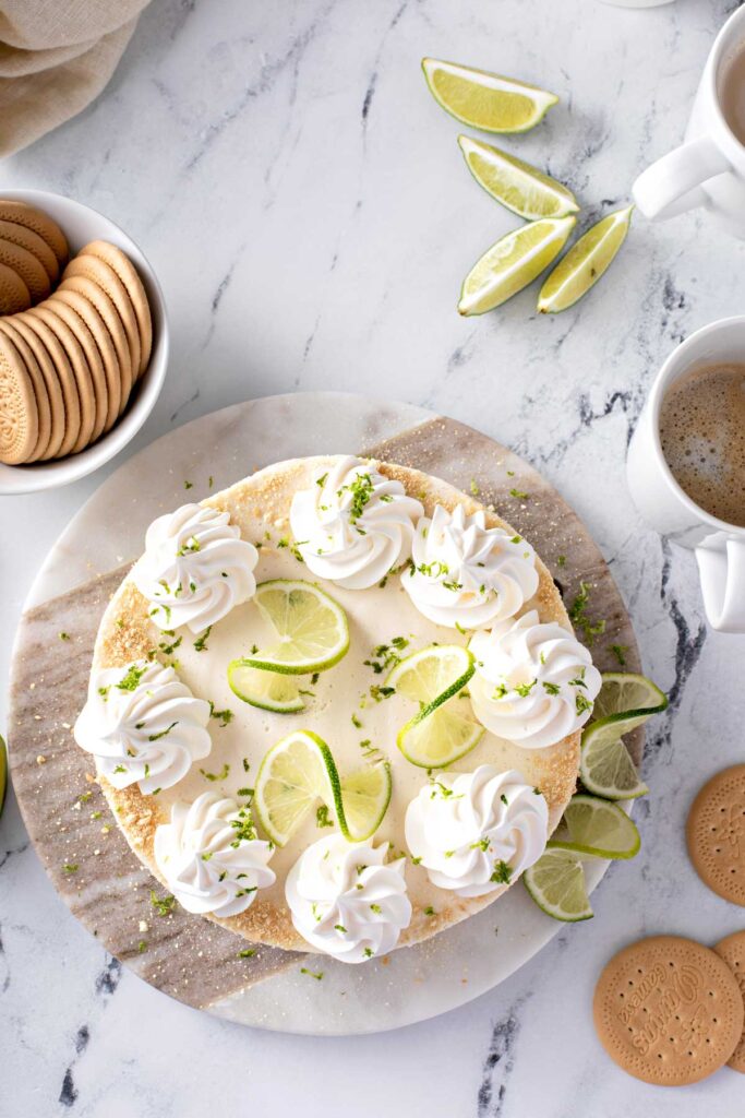 Top view of a beautiful Carlota de Limón dessert topped with rodajas de limón (lime slices), whipped cream and galletas trituradas (cookie crumbles)