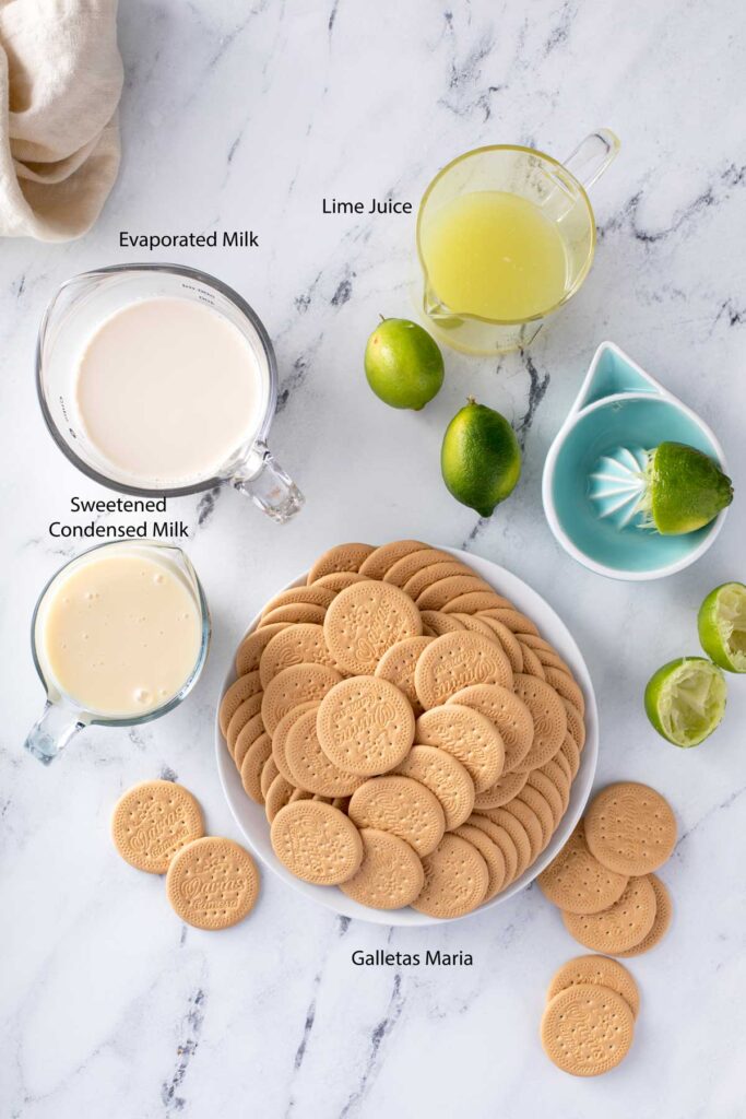 Ingredients to make Mexican Carlota de Limón cake with galletas Maria, limes and sweetened condensed milk (leche condensada) and evaporated milk (leche evaporada).