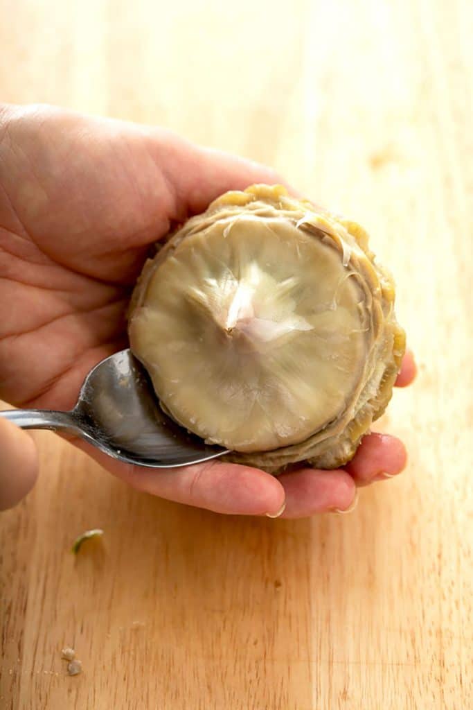 scraping off the choke of an artichoke with a spoon
