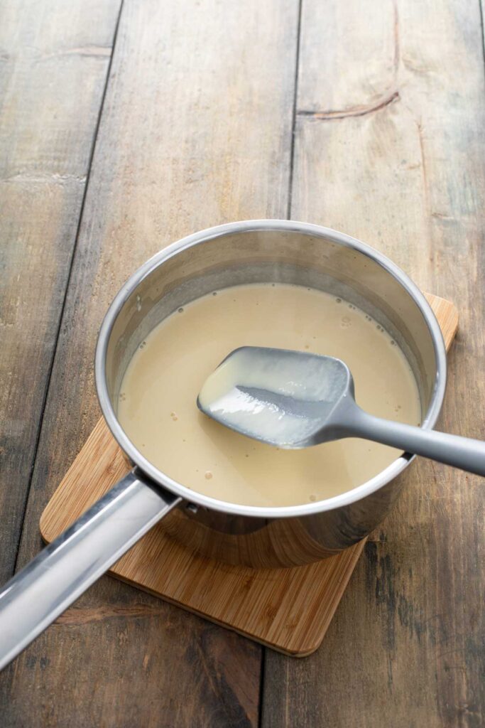 Ice cream base in a saucepan with a spatula showing the custard is perfectly cooked.