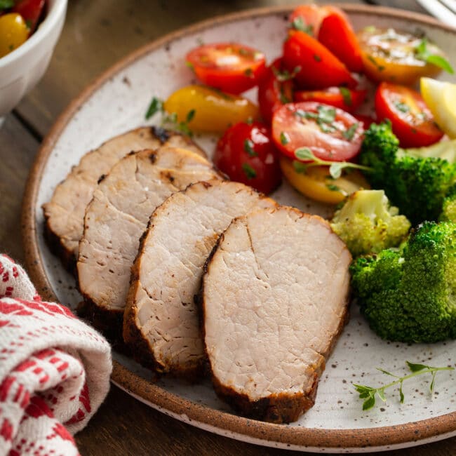 Pork tenderloin slices served with tomatoes and broccoli