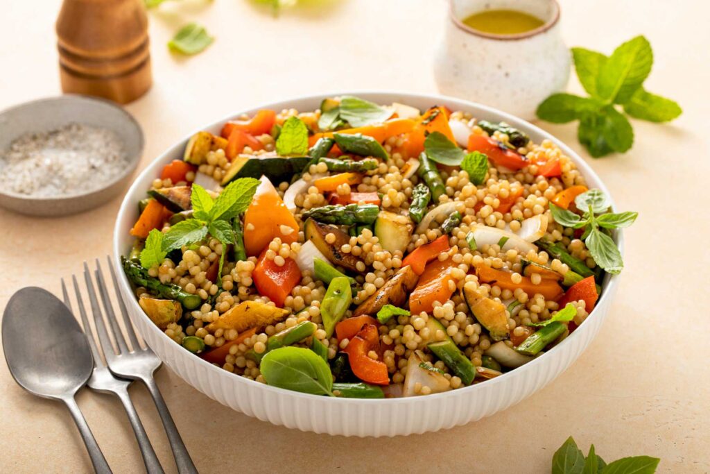 a bowl filled with cooked pearl couscous and grilled vegetables