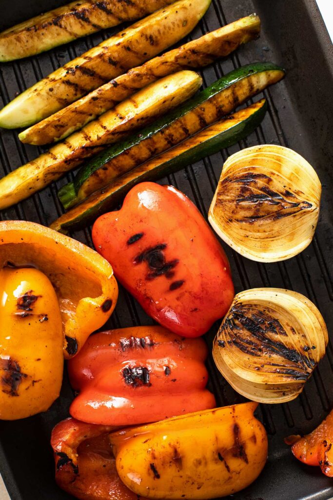 Caramelized and grilled marked grilled bell peppers, onions, zucchini and yellow squash on a grill pan