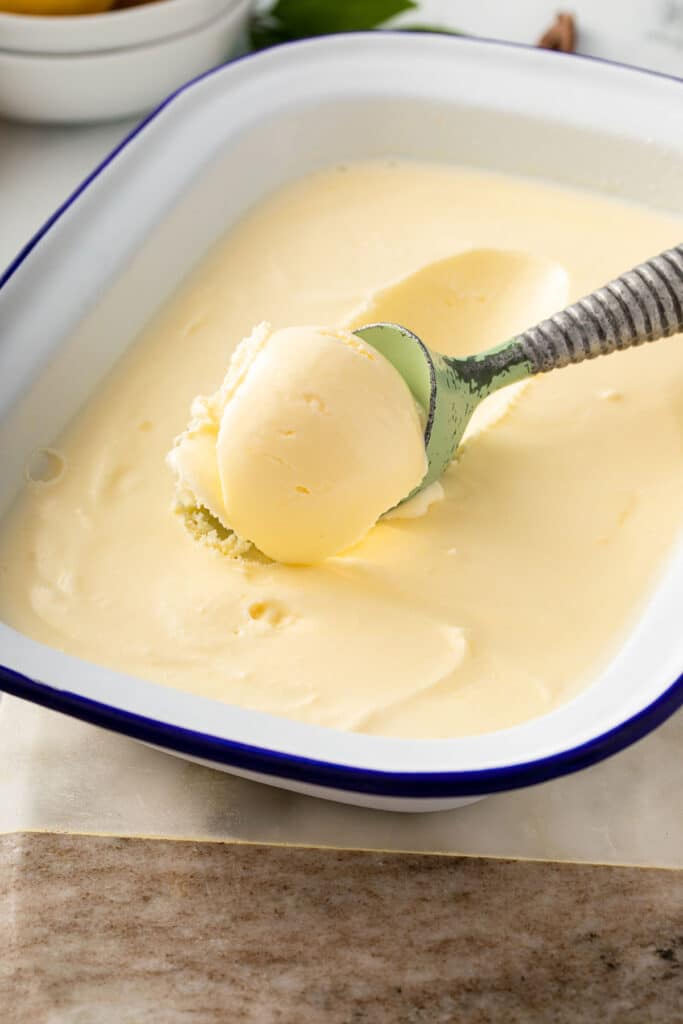 Scooping creamy lemon ice cream from a container