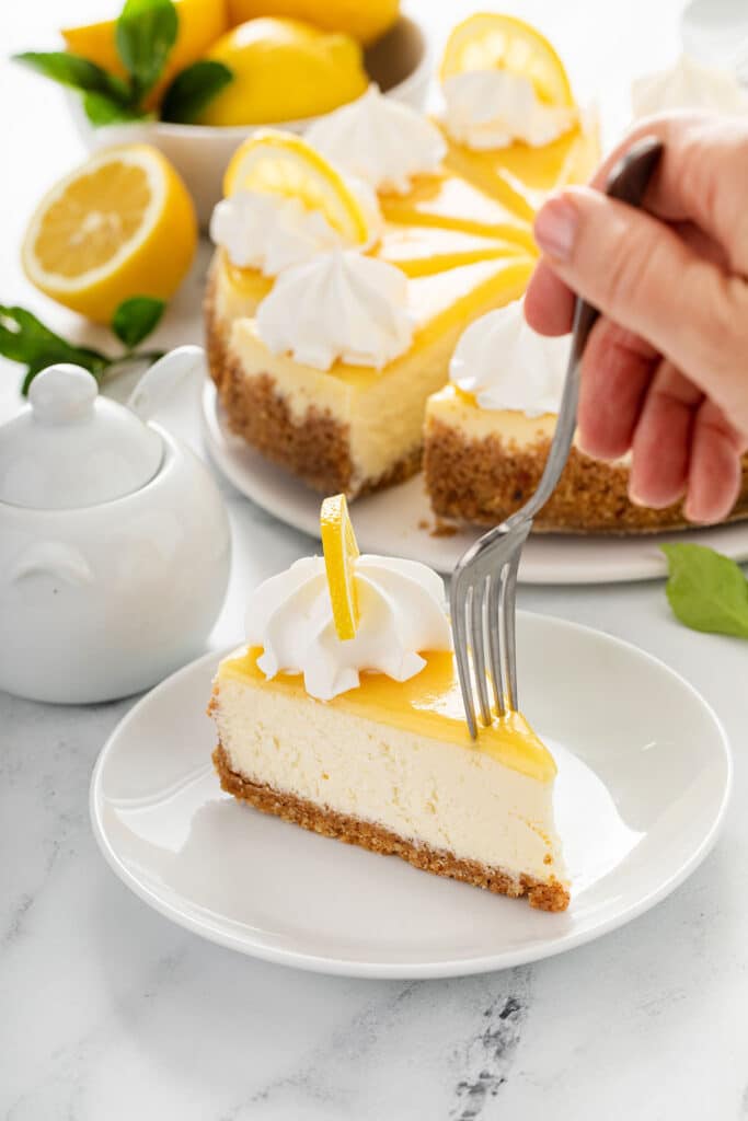 Getting a piece of lemon cheesecake with a dessert fork.