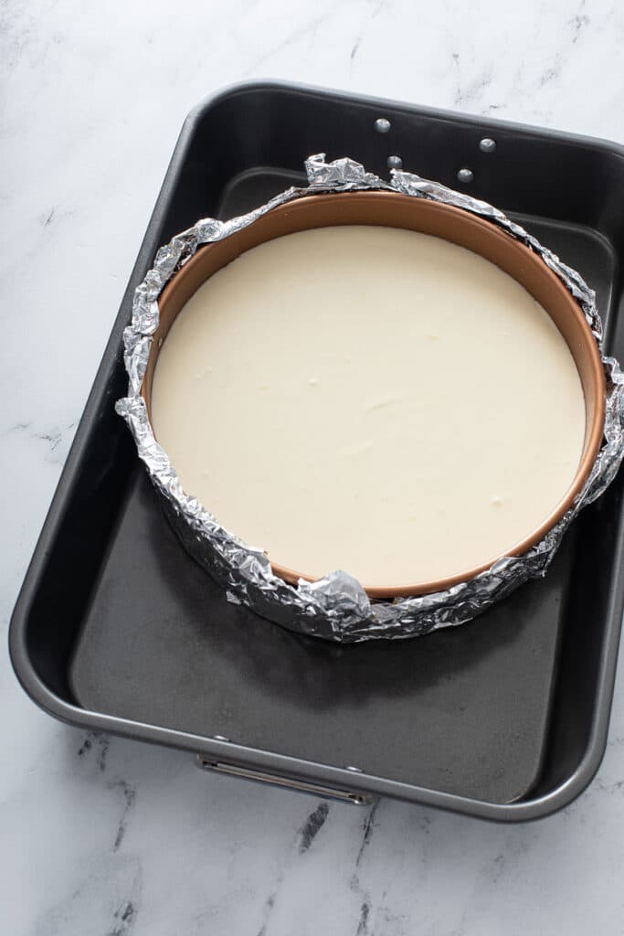 lemon cheesecake with tented with foil sitting in water bath ready to be baked 