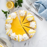 Top view of a sliced lemon cheesecake topped with whipped cream