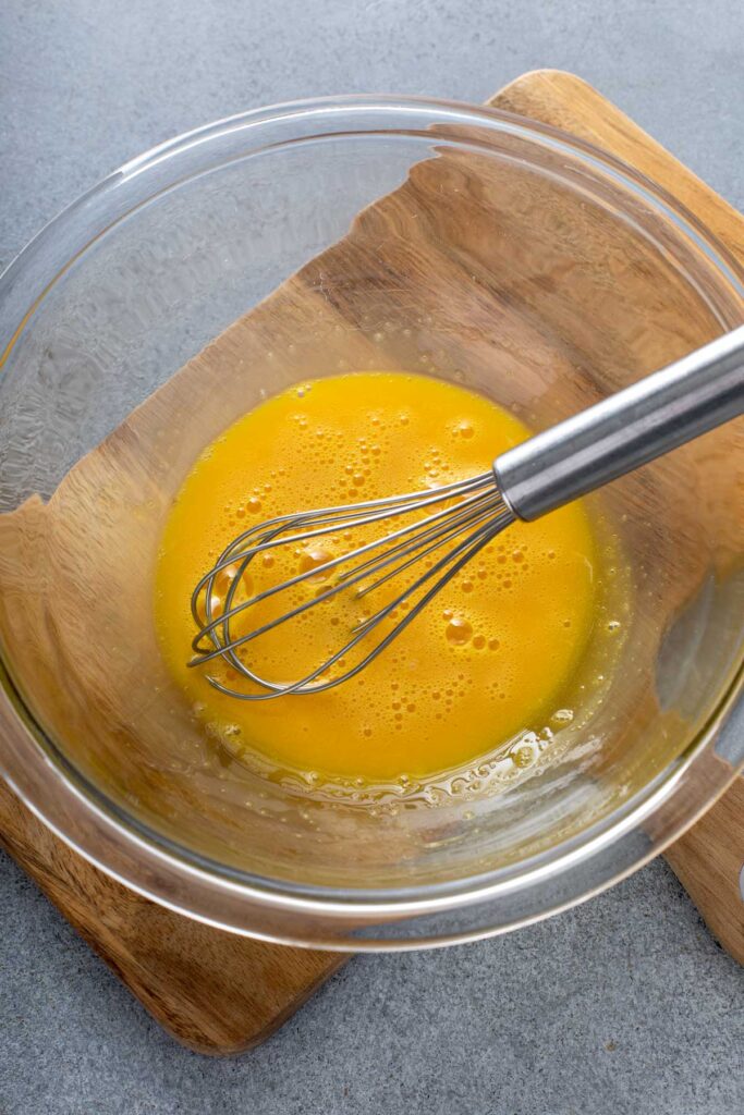 egg yolks, sugar, and salt whisked together in a glass bowl for raspberry ice cream 
