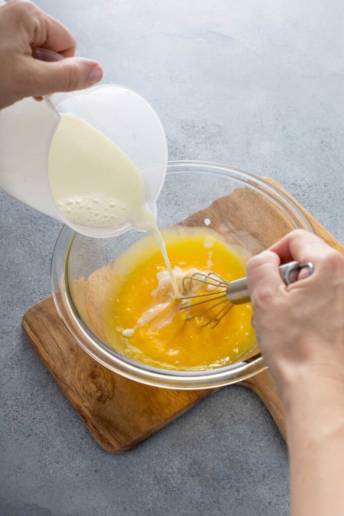 hot cream being poured slowly into the glass bowl  with egg mixture.  