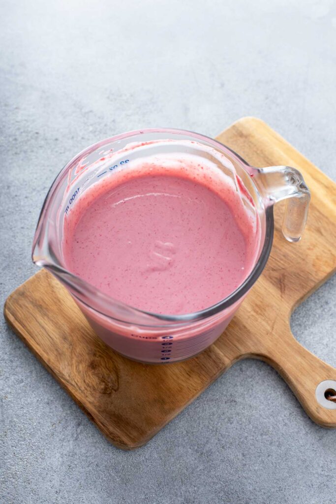 Raspberry ice cream custard in a glass measuring cup, ready to cool and churn.