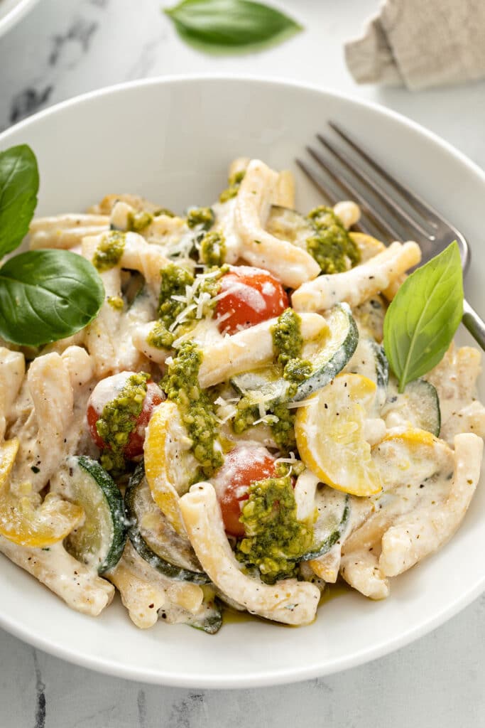 Summer squash and cherry tomatoes tossed with short pasta and creamy ricotta parmesan sauce then topped with basil pesto.