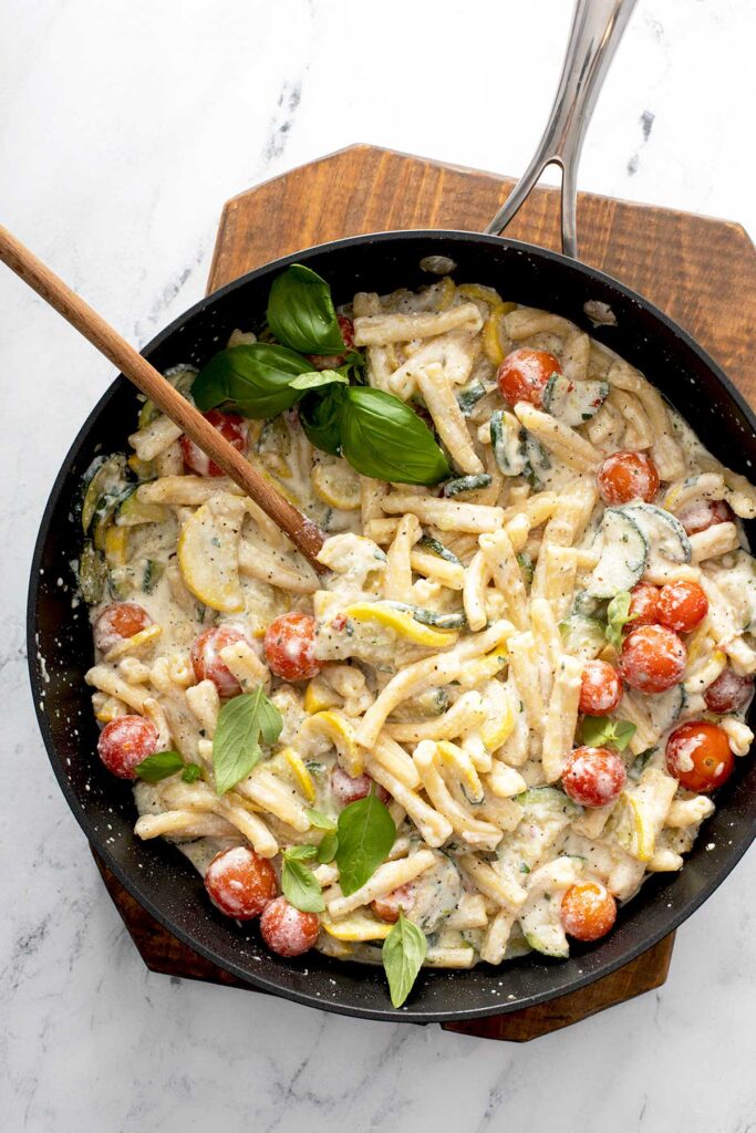 Pasta tossed with tender zucchini, yellow squash and cherry tomatoes with a creamy cheese sauce in a skillet