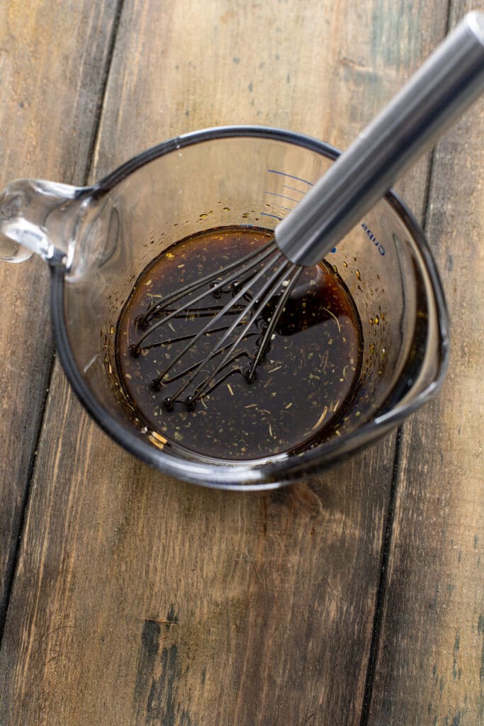 steak marinade in a measuring cup with a whisk