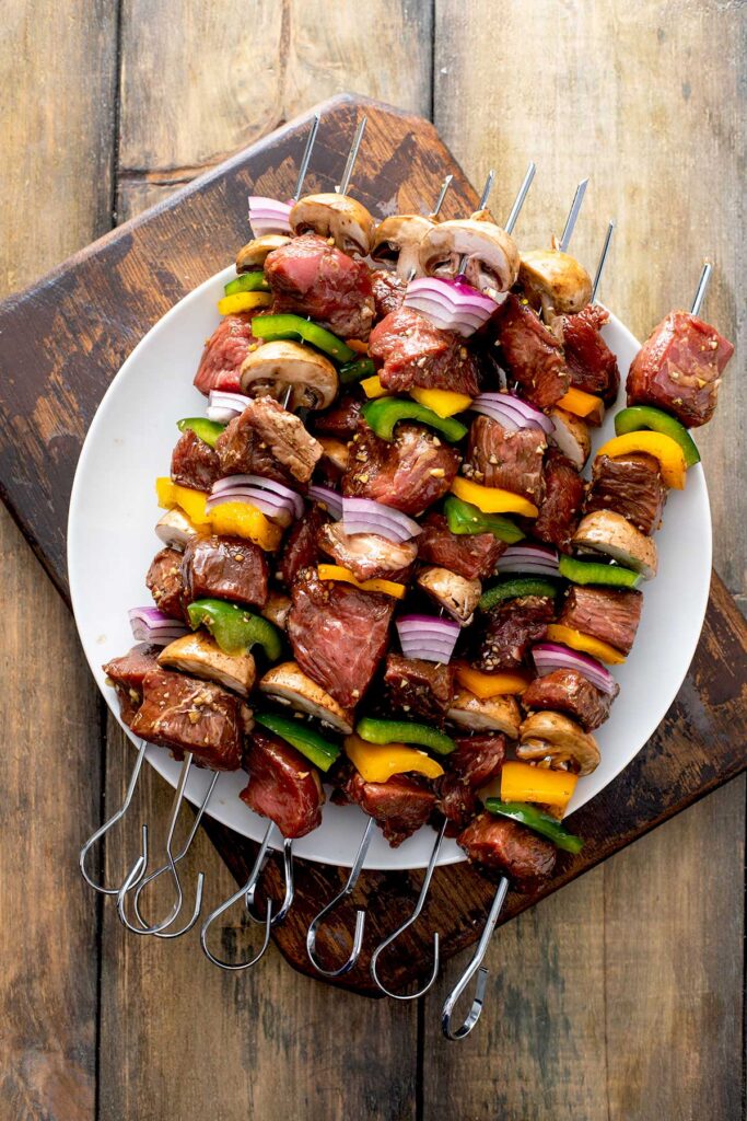 skewers of steak and vegetables  on a plate waiting to be grilled