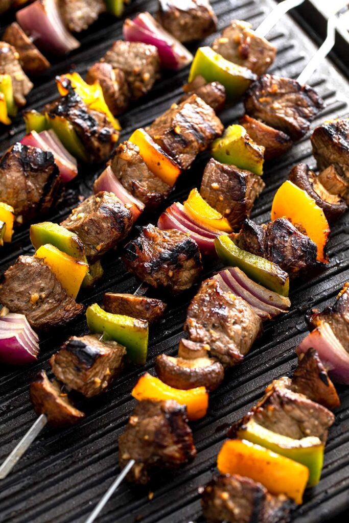 Steak and vegetables on skewers over a hot grill