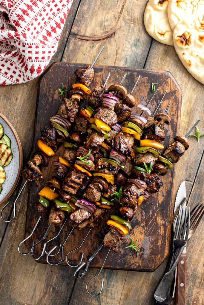Grilled beef steak and veggies kabobs on a wooden board