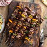 beef steak kebabs with vegetables on a wooden board