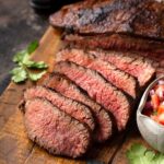 Thin sliced of grilled tri-tip on a cutting board