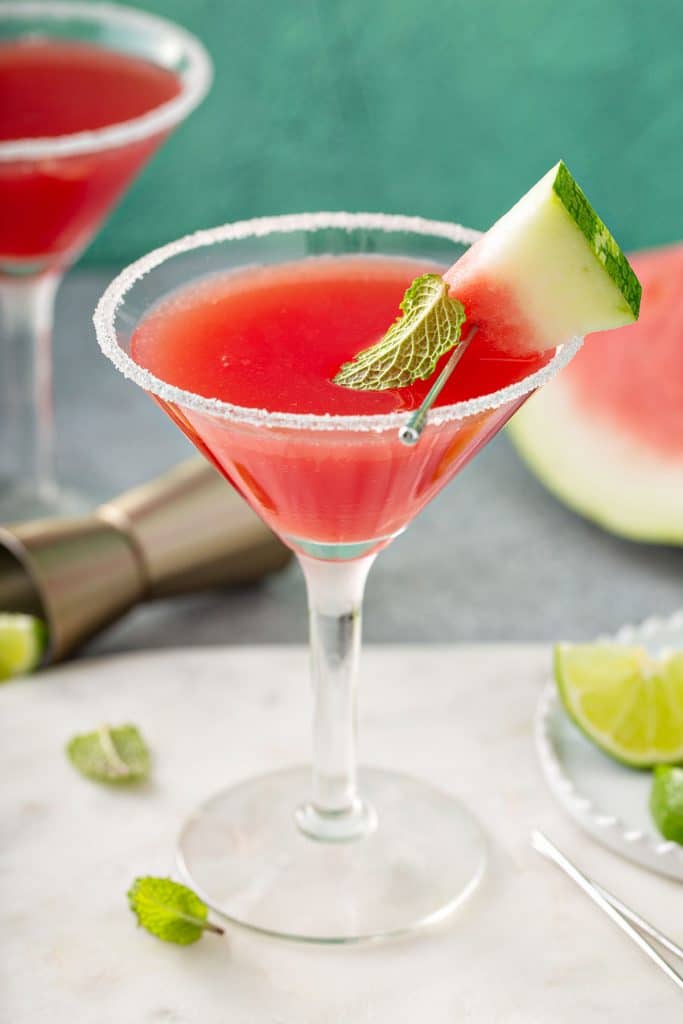 Watermelon martini served in a martini glass and decorated with a piece of watermelon and sugar on the rim.