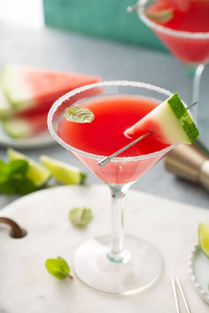 Watermelon Martini served in a martini glass and decorated with a piece of watermelon, sugar on the rim and a mint leaf.