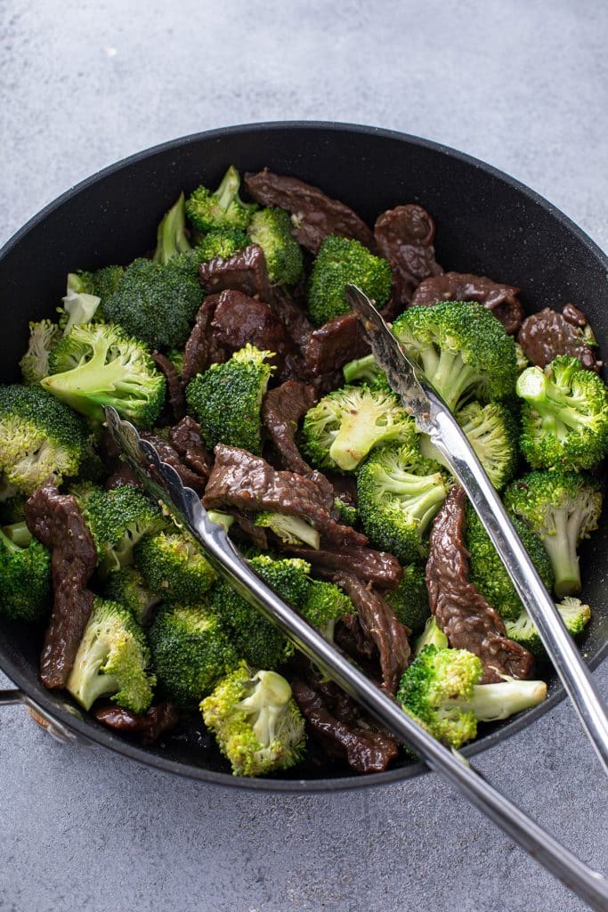 Beef with Broccoli on a skillet with tongs 