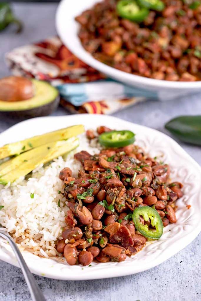 Mexican charo beans with bacon served with white rice and avocado slices
