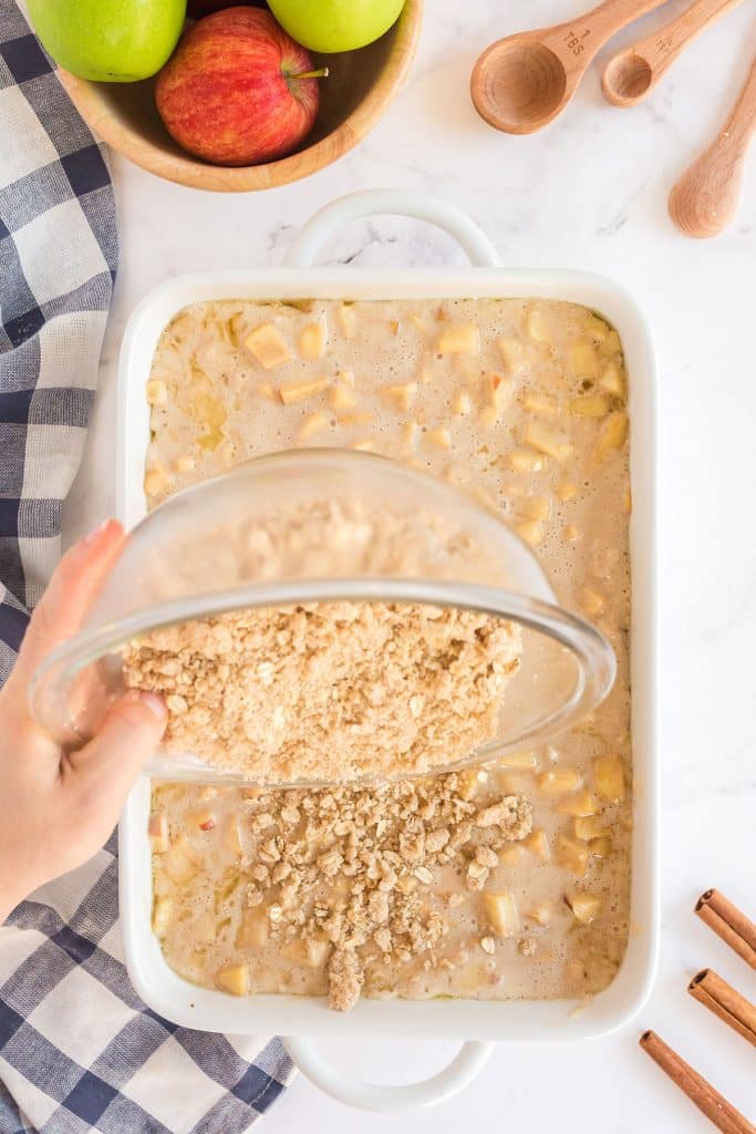 pouring the oats topping over the batter mixed with apples