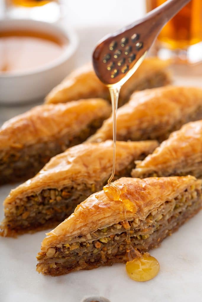 Diamond shaped Baklava getting drizzled with honey.