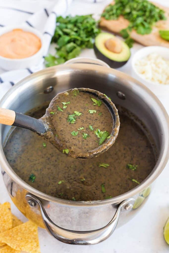 Scooping black bean soup from the pot with a ladle