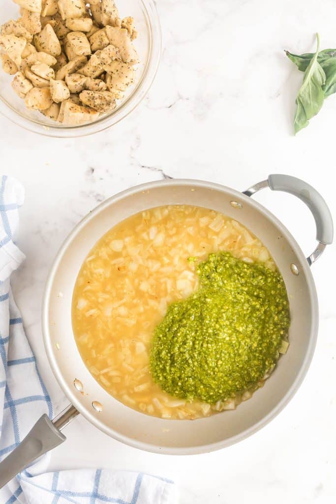 pouring pesto sauce over the broth