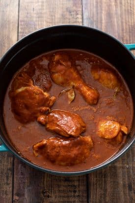 Browned chicken covered in chile sauce inside a pot