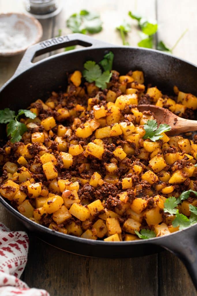 A cast iron skillet filled with tender potatoes and chorizo tossed together.