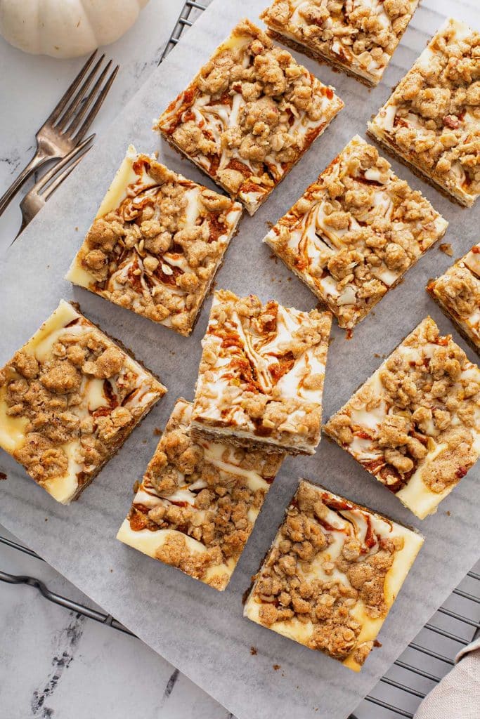 Cheesecake Bar squares on parchment paper on a cooling rack.