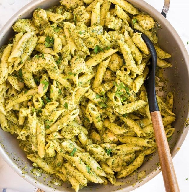 Creamy pasta with chicken and pesto sauce in a skillet.