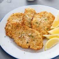 Crispy and golden brown chicken cutlets on a plate sprinkled with Parmesan cheese