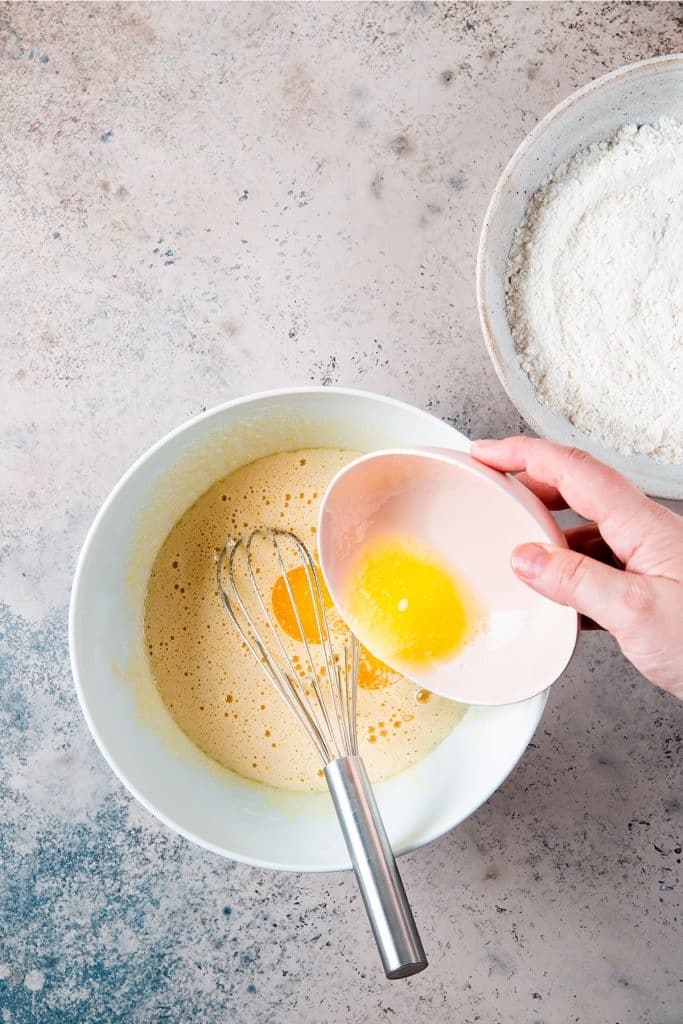 Adding melted butter to the egg mixture.