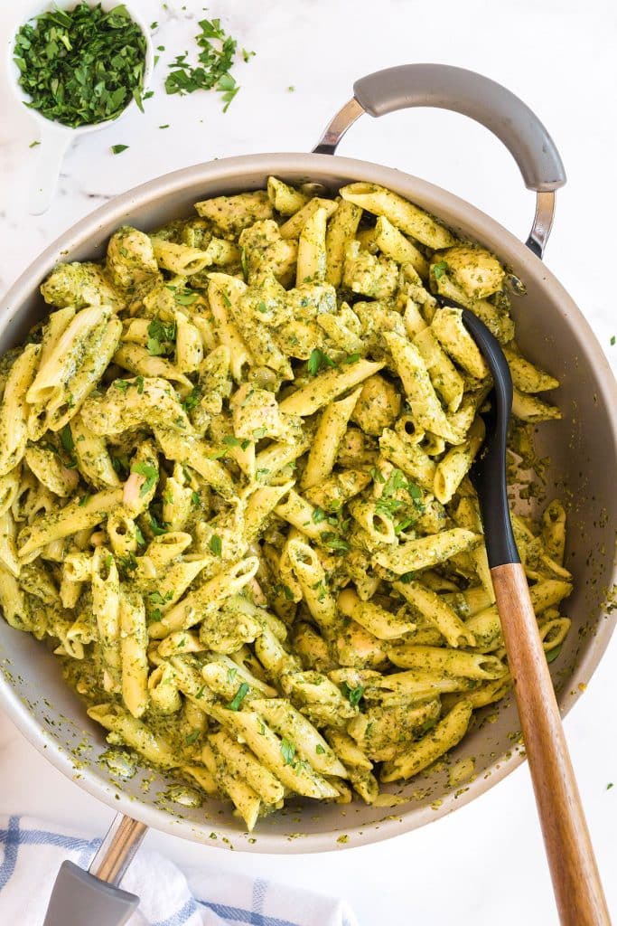 Skillet filled with creamy pasta with tender, juicy sautéed chicken tossed with cream and basil pesto sauce.