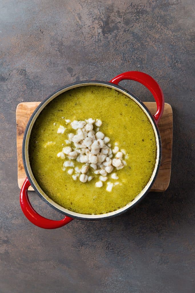 Stirring hominy into pozole verde.