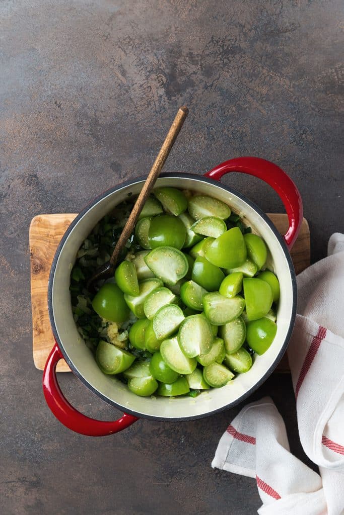 tomatillos cut in half over the sauteed chiles