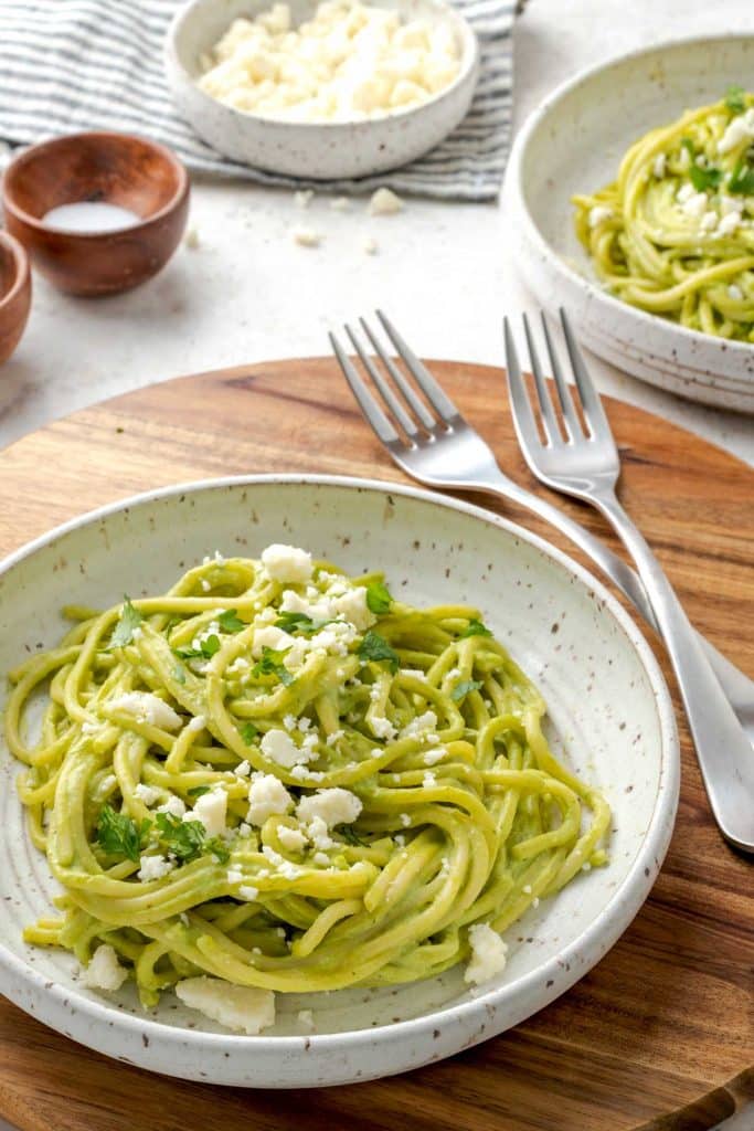 Spaghetti verde served on a bowl and topped with crumbled cheese